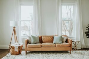 Cognac leather sofa seated in front of white wall and two window on white carpet, therapyworthwhile