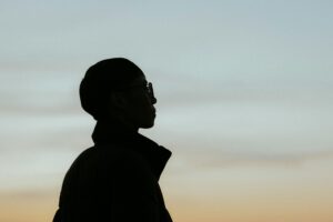 Silhouette of short-haired woman, outside, staring off at the horizon, at sunset, therapyworthwhile