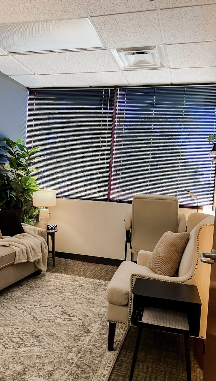 Cozy therapy consultation room of Alexis Lynne Jardine featuring a comfortable sofa, warm lighting, and a large window.