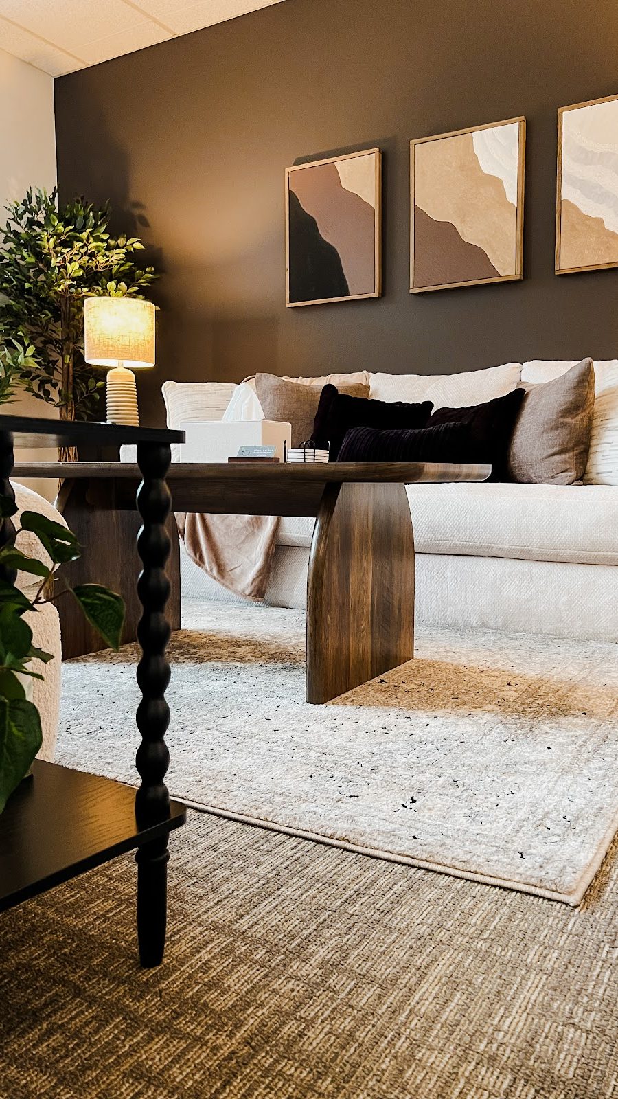 Therapy Worthwhile modern counseling office with a beige sofa and dark accent wall.